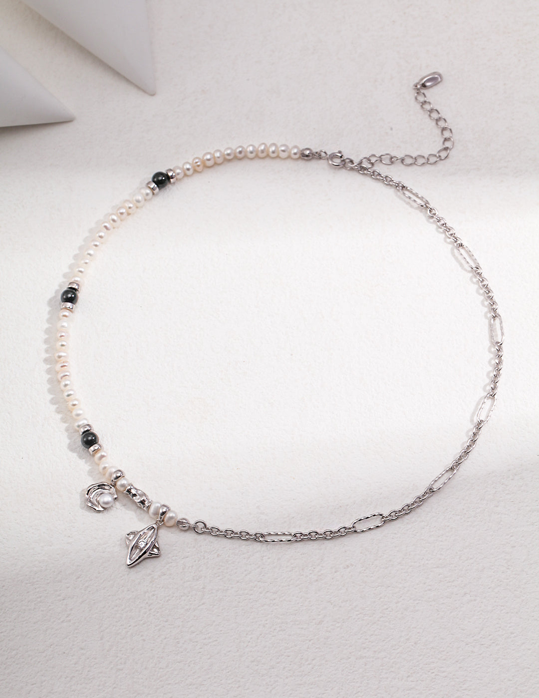 A silver necklace featuring celestial elements and freshwater pearls.
