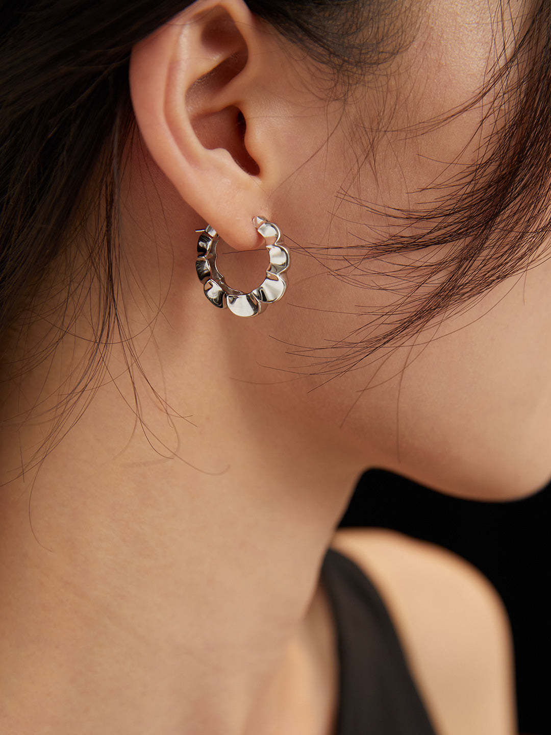 Silver chain earrings adorned with floral hoops on model.