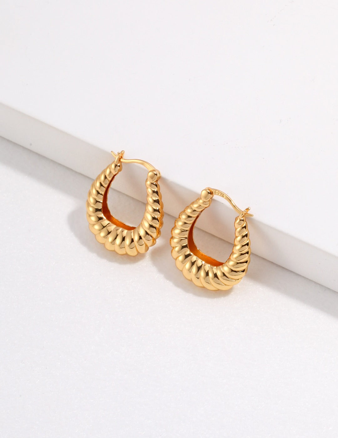 Stylish gold plated hoop earrings with a unique twisted design, ideal for a chic look.
