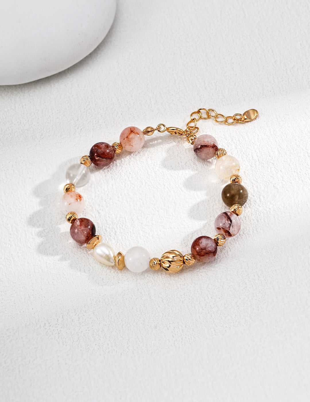 Stylish bracelet made of natural stones, gold-plated chain, and various beads, displayed against a clean white background.