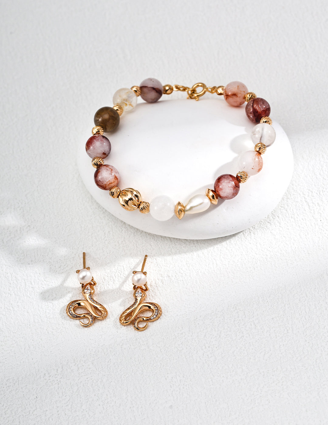 Elegant bracelet and earrings set with gold accents, faceted beads, and pearls, displayed on a clean white background.