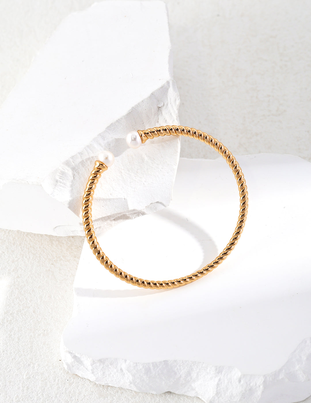 A gold twisted bangle with pearls, a stunning accessory for any occasion.