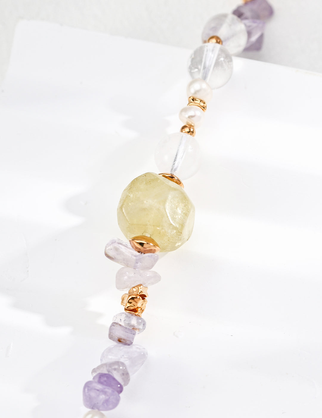 Detailed view of a necklace showcasing purple amethyst and yellow citrine beads, accented with clear quartz round beads.