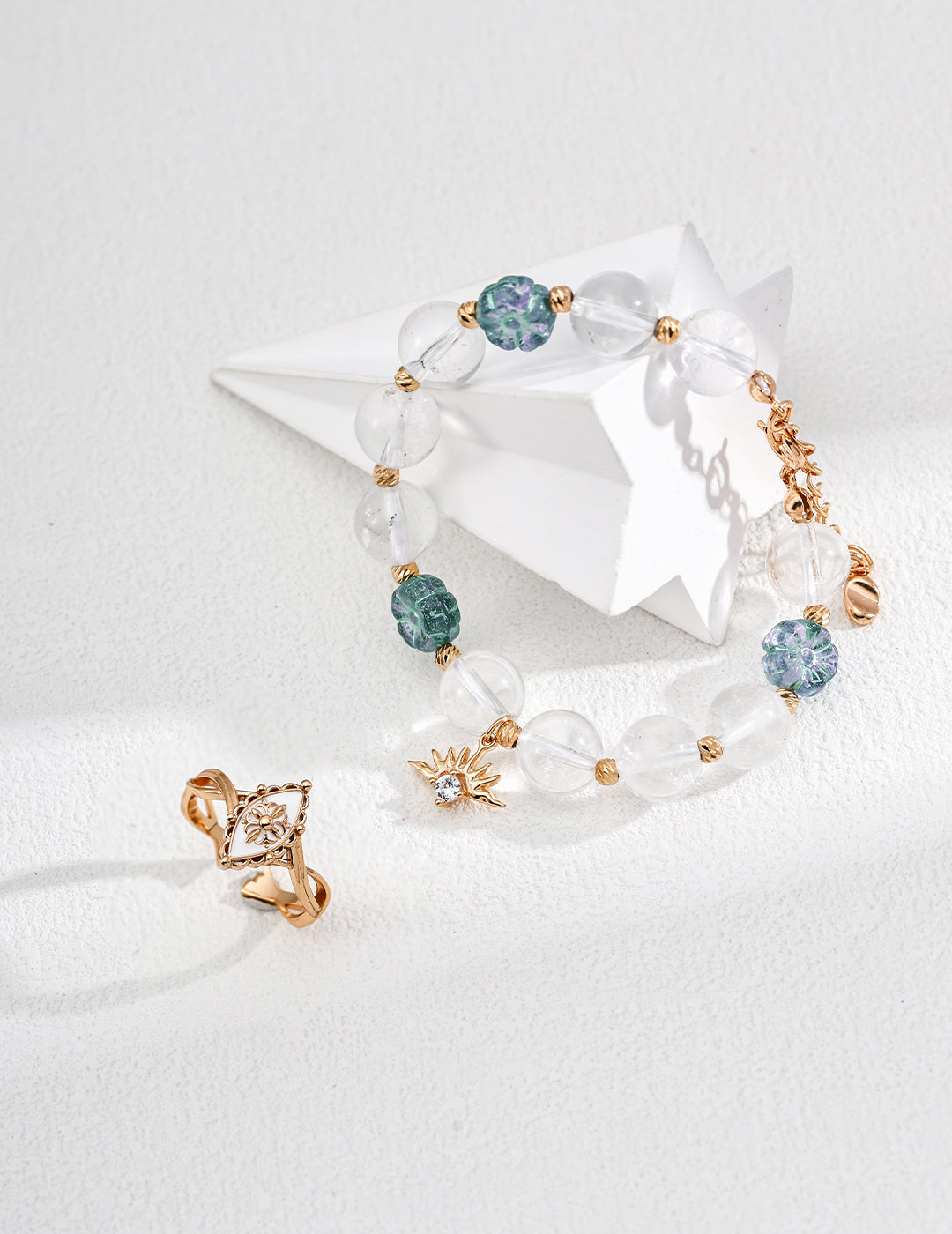 A bracelet showcasing gold and blue stones, made with clear quartz round beads and flower-shaped glass accents.