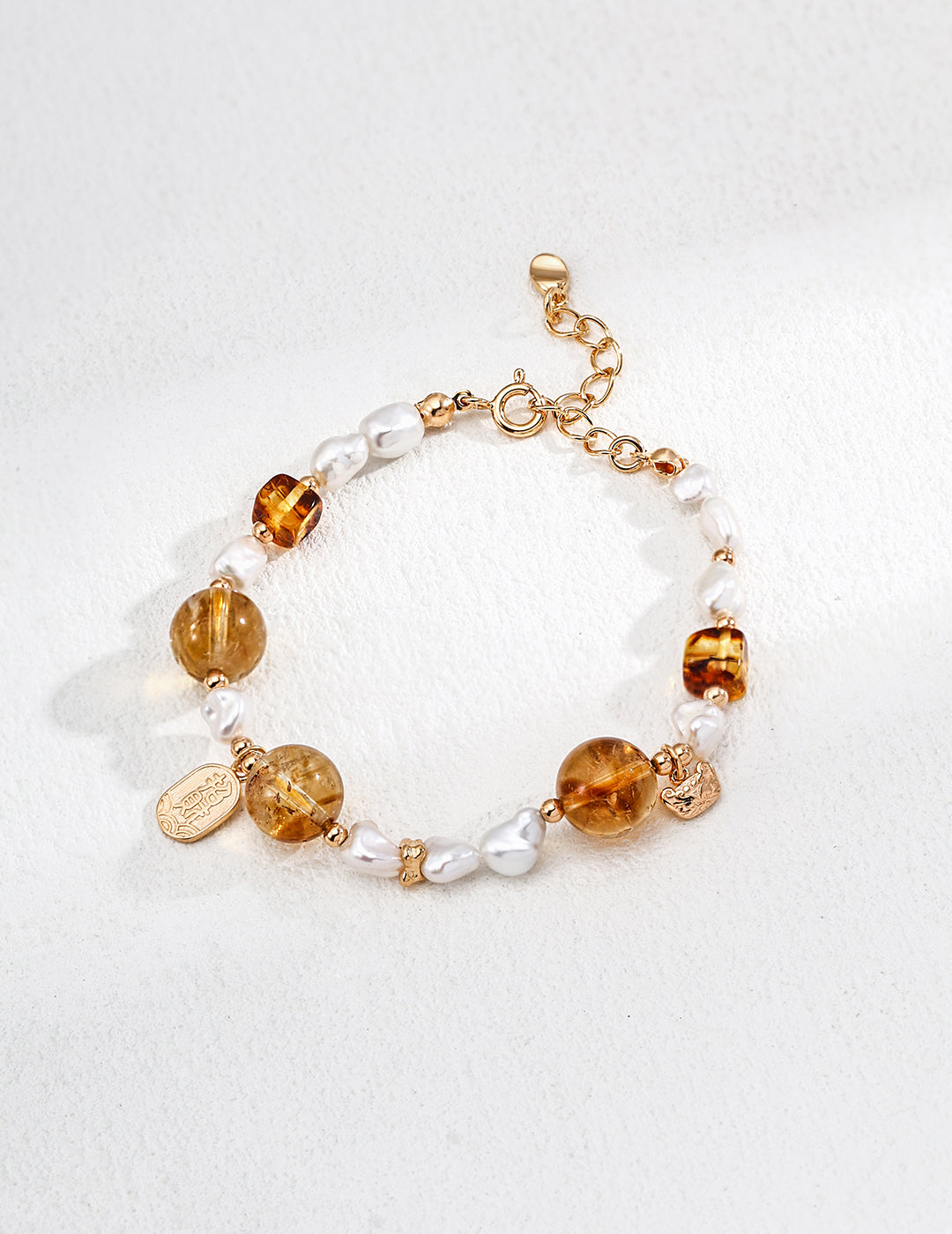 A bracelet featuring gold and white beads, tiger's eye stones, and pearls, elegantly arranged for a stylish look.