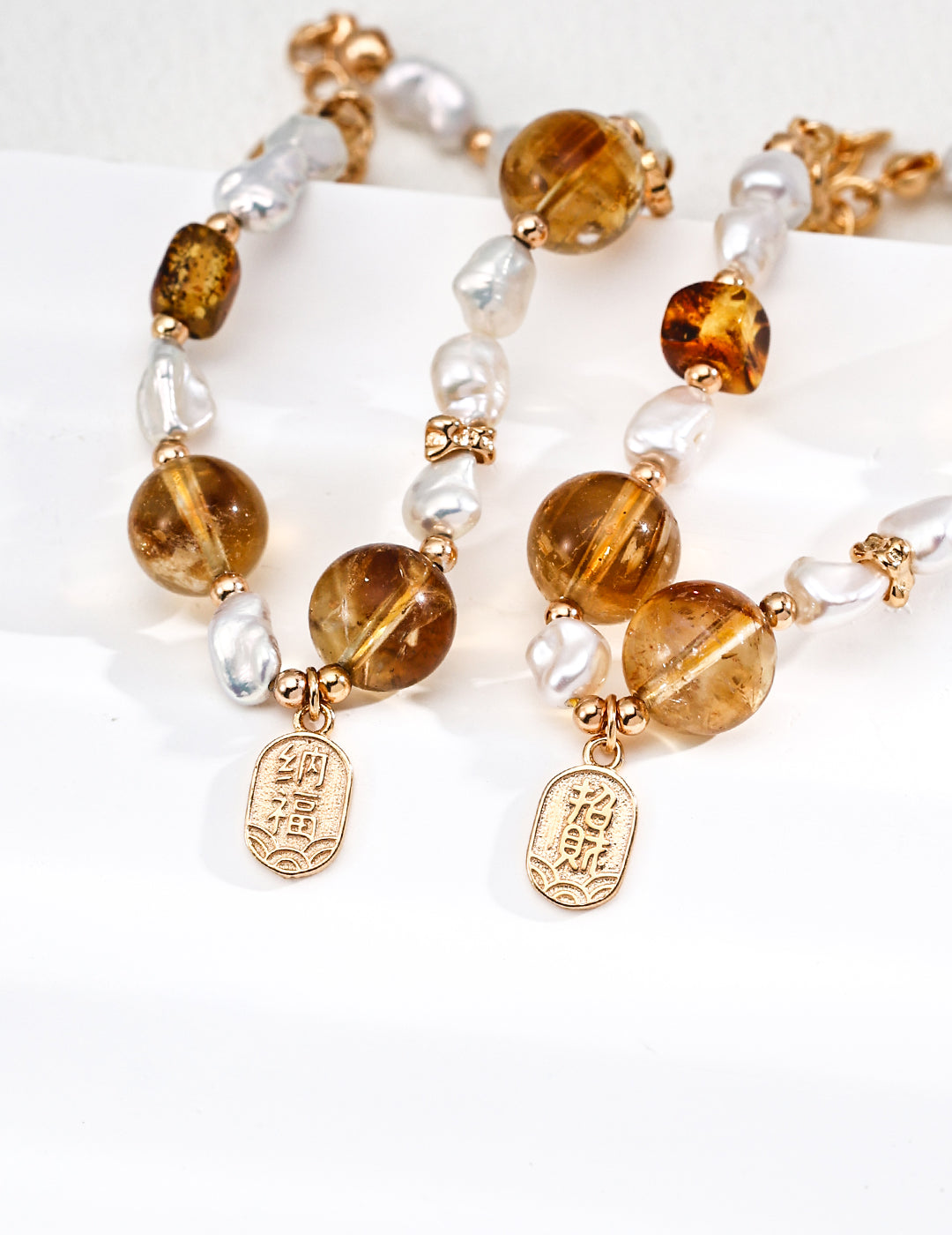 Two elegant gold-plated bracelets with a crystal charm, embellished with tiger's eye and pearl details.