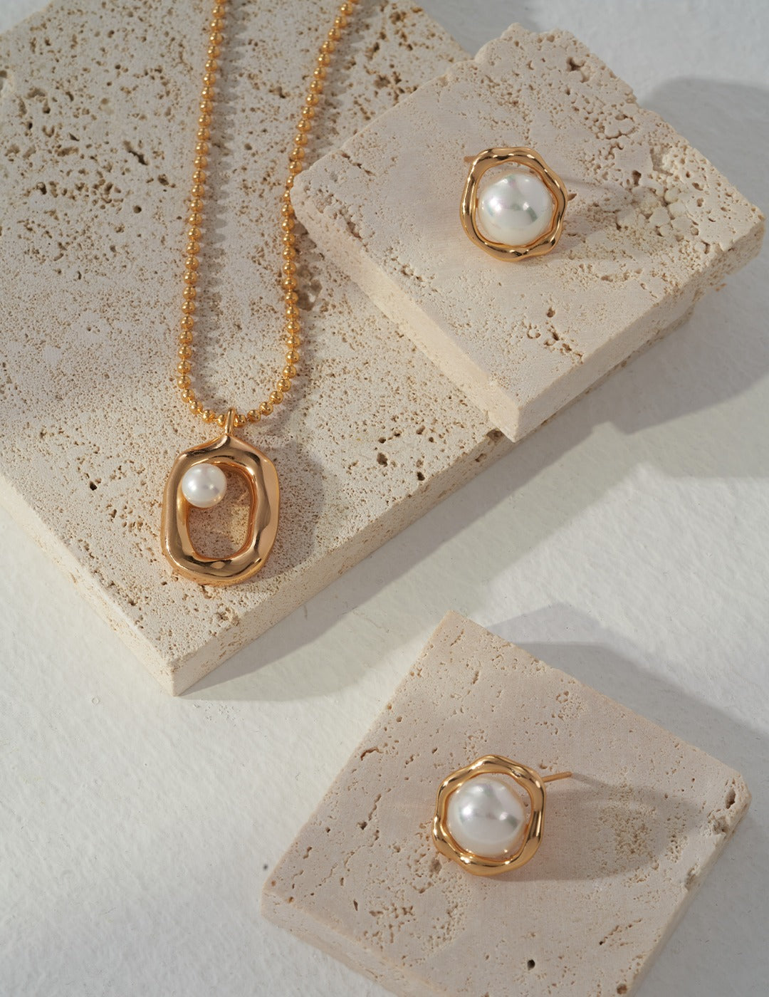 A stunning jewelry set featuring a gold necklace, sunny side up earrings, and a delicate pearl pendant, all in harmony.