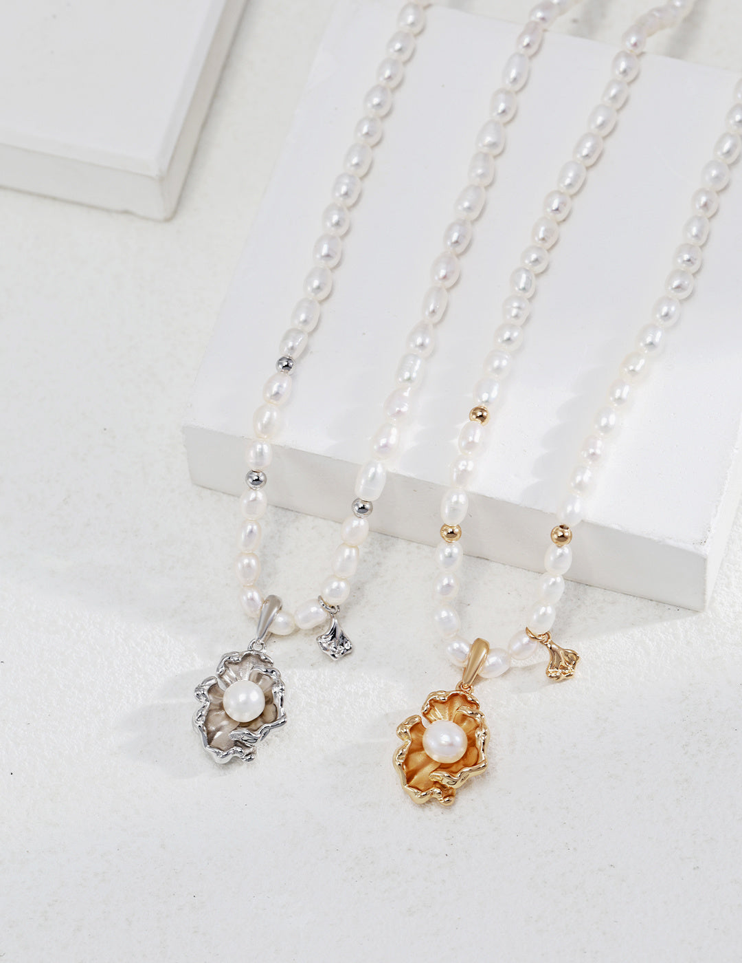 Two stunning gold necklaces adorned with pristine white pearls, highlighting the luxurious contrast of silver and gold.