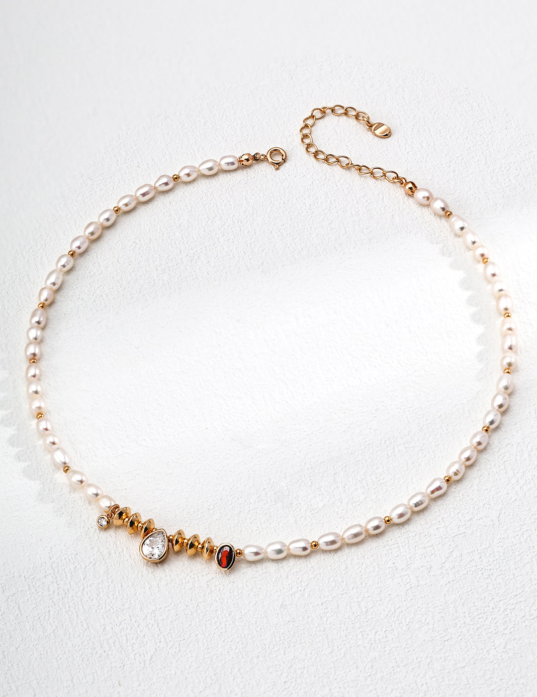 Regal gold and white pearl necklace showcasing a vibrant red and white stone, complemented by cubic zirconia and freshwater pearls.