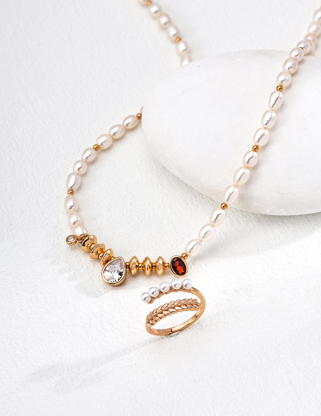 Stunning necklace showcasing a gold teardrop ring, freshwater pearls, and cubic zirconia, exuding a royal vibe.