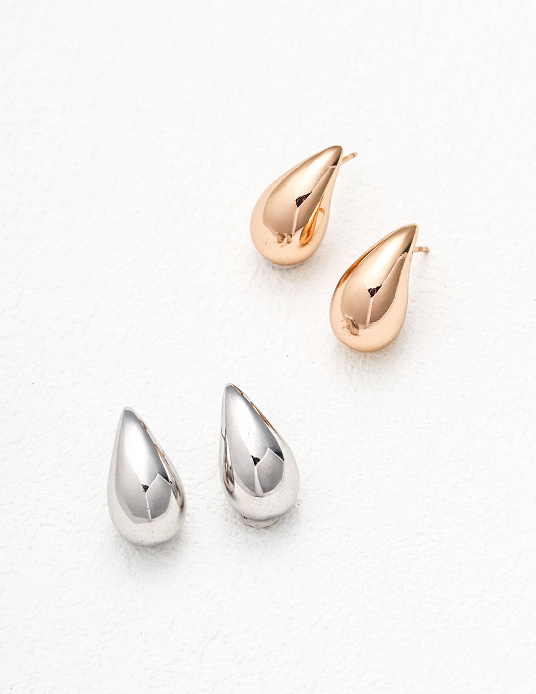 Two pairs of tear-shaped earrings in gold and silver.