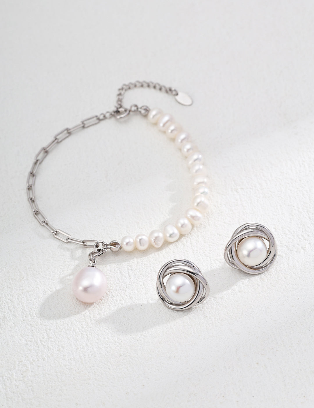 Stunning silver jewelry set featuring a pair of pearl earrings and a matching bracelet, ideal for a sophisticated look.