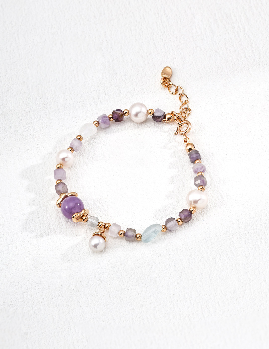 A stylish bracelet adorned with purple and white beads, including amethyst and icy aquamarine, plus a pearl centerpiece.