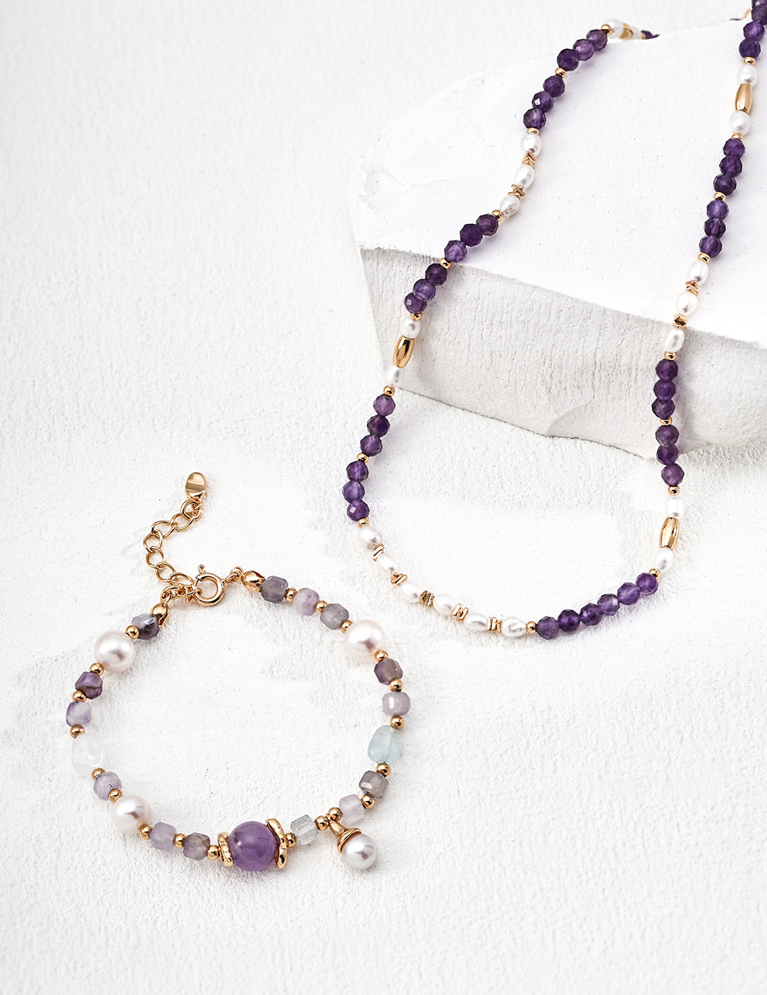 A set of purple jewelry including a necklace, bracelet, and earrings displayed together.