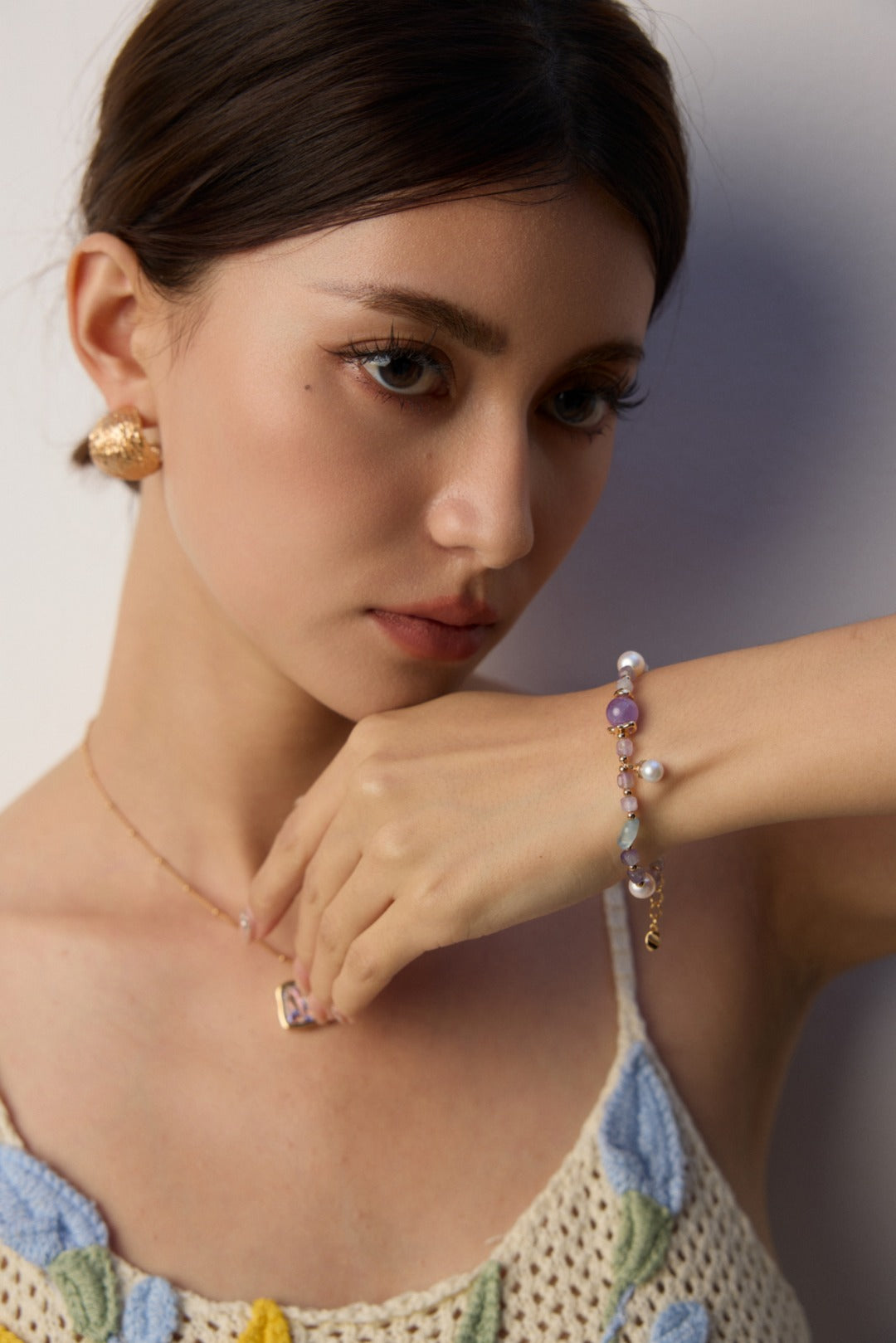 A woman wearing a stylish necklace and matching bracelet, showcasing her elegant accessories.