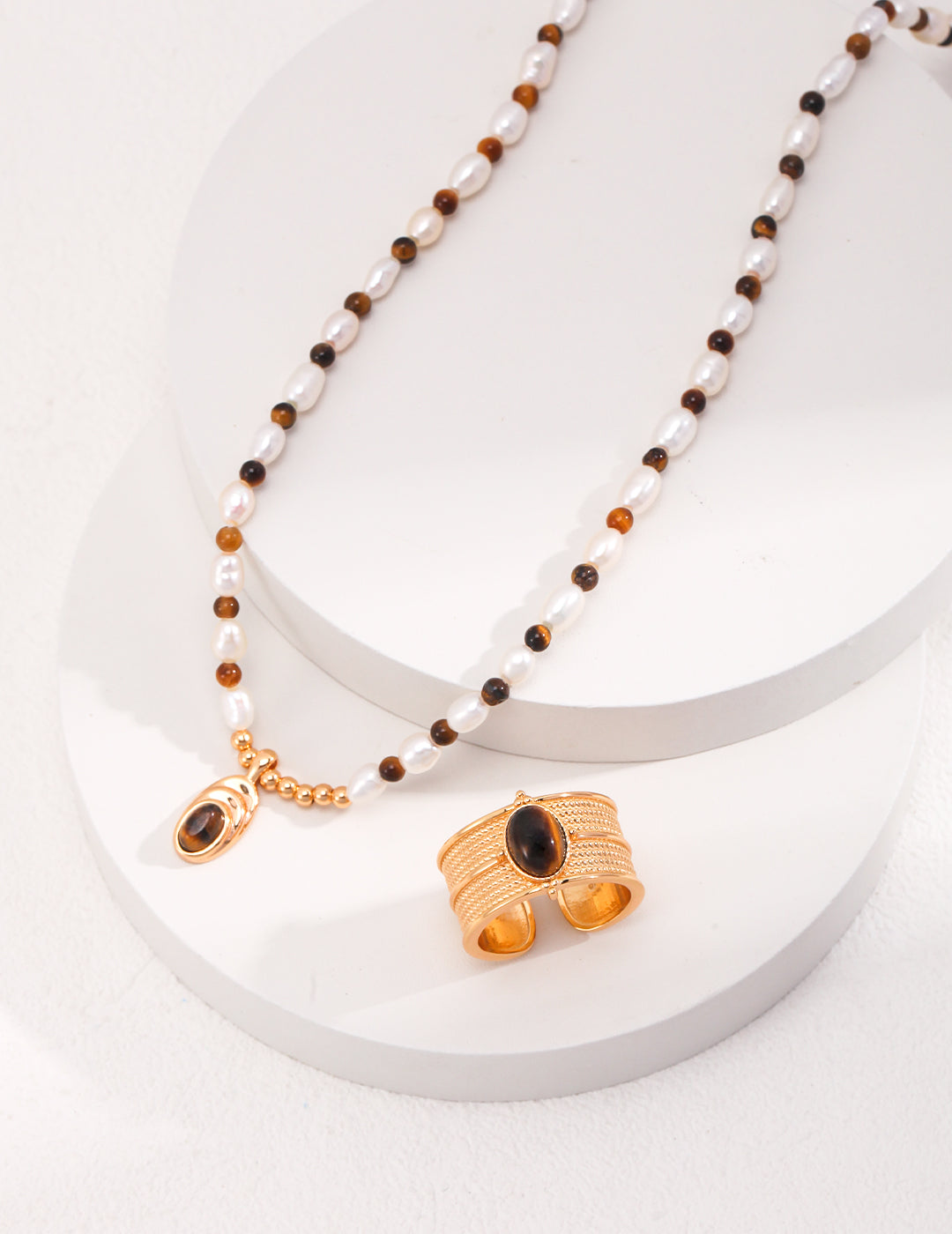 Elegant gold chain jewelry set featuring tiger's eye and freshwater pearl beads, with a matching chunky ring.