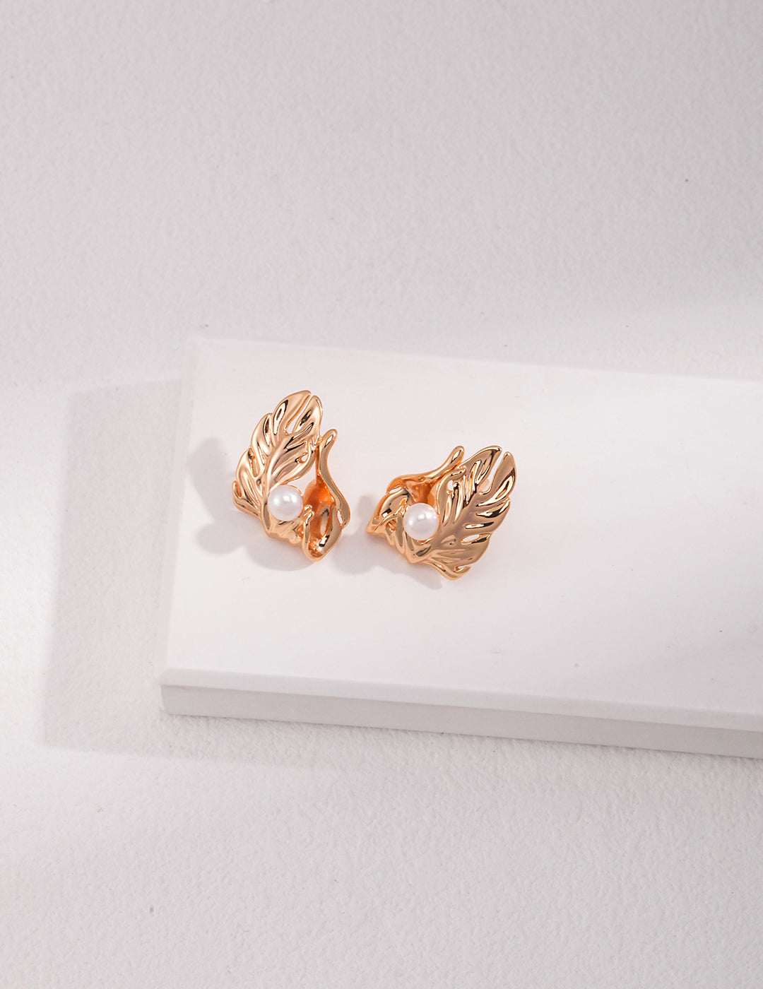 A pair of gold tone earrings adorned with delicate leaf motifs, perfect for adding a touch of nature to any outfit.