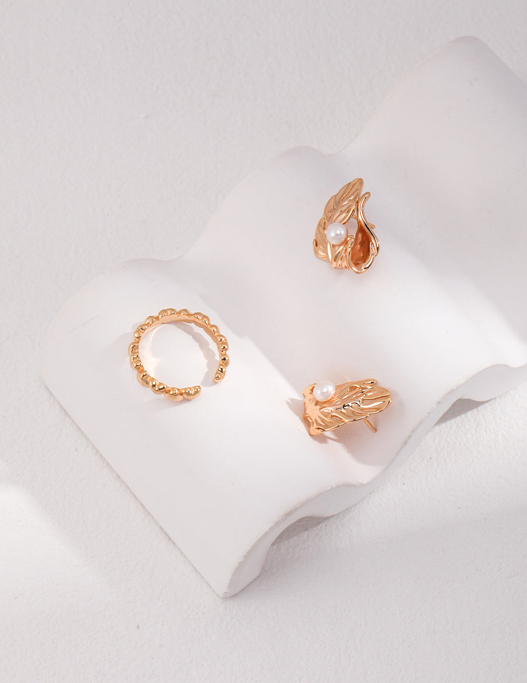 Shimmering gold ring and earrings arranged on a clean white surface, emphasizing their beauty and unique styles.