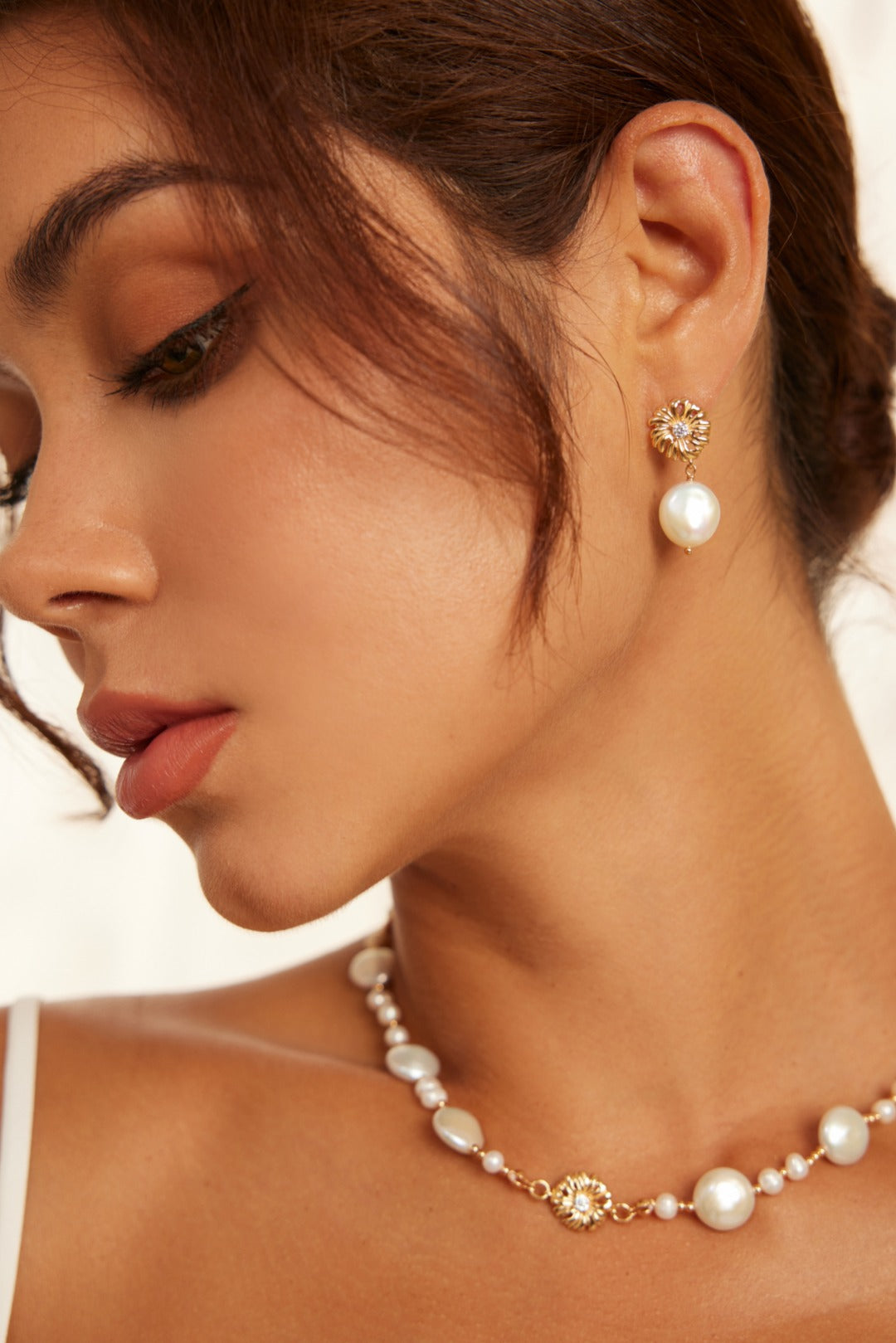 A woman adorned with a necklace and floral pearl earrings, highlighting her fashionable look.