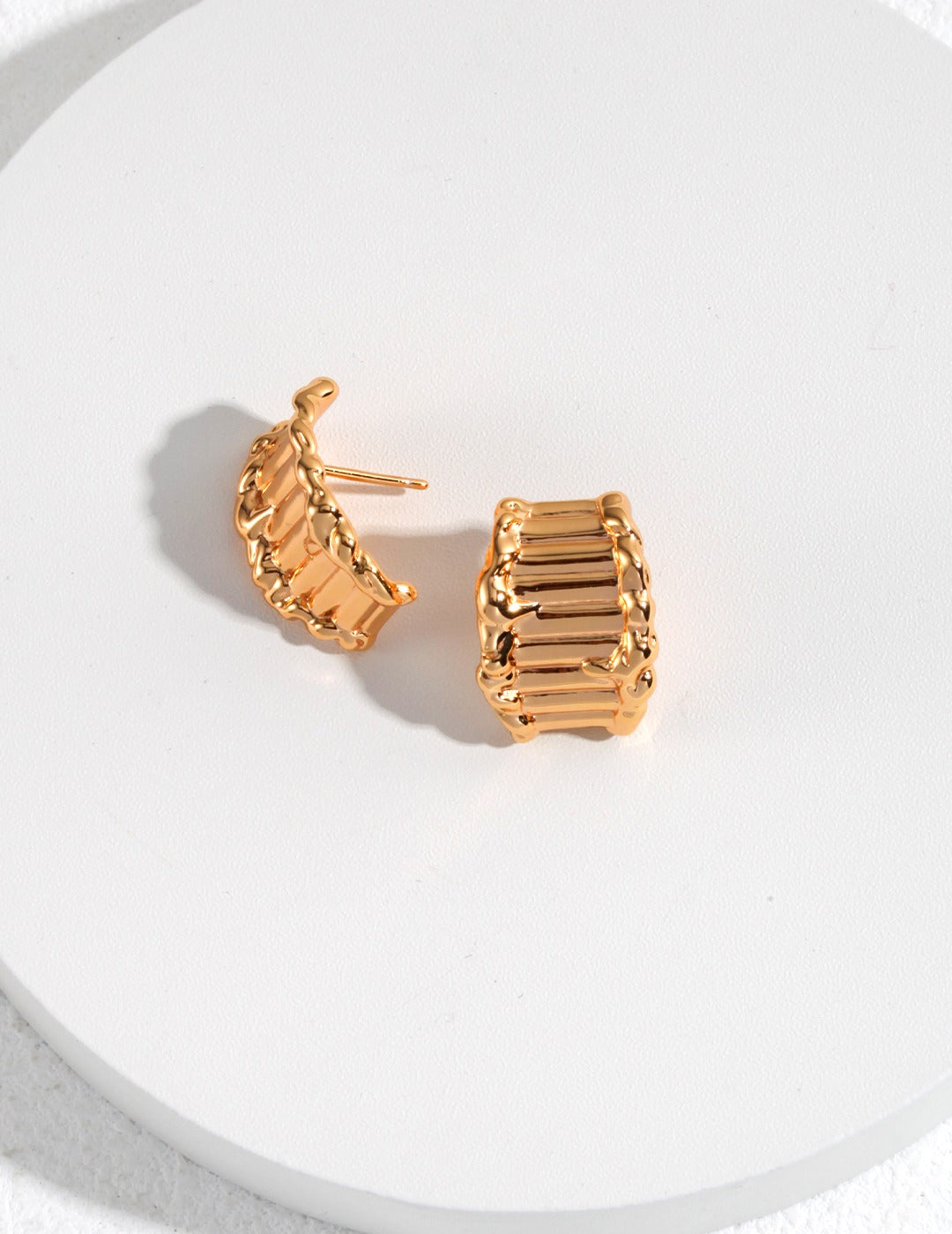 Chic gold plated earrings on a white surface - featuring trendy crescent shapes for a fashionable look.