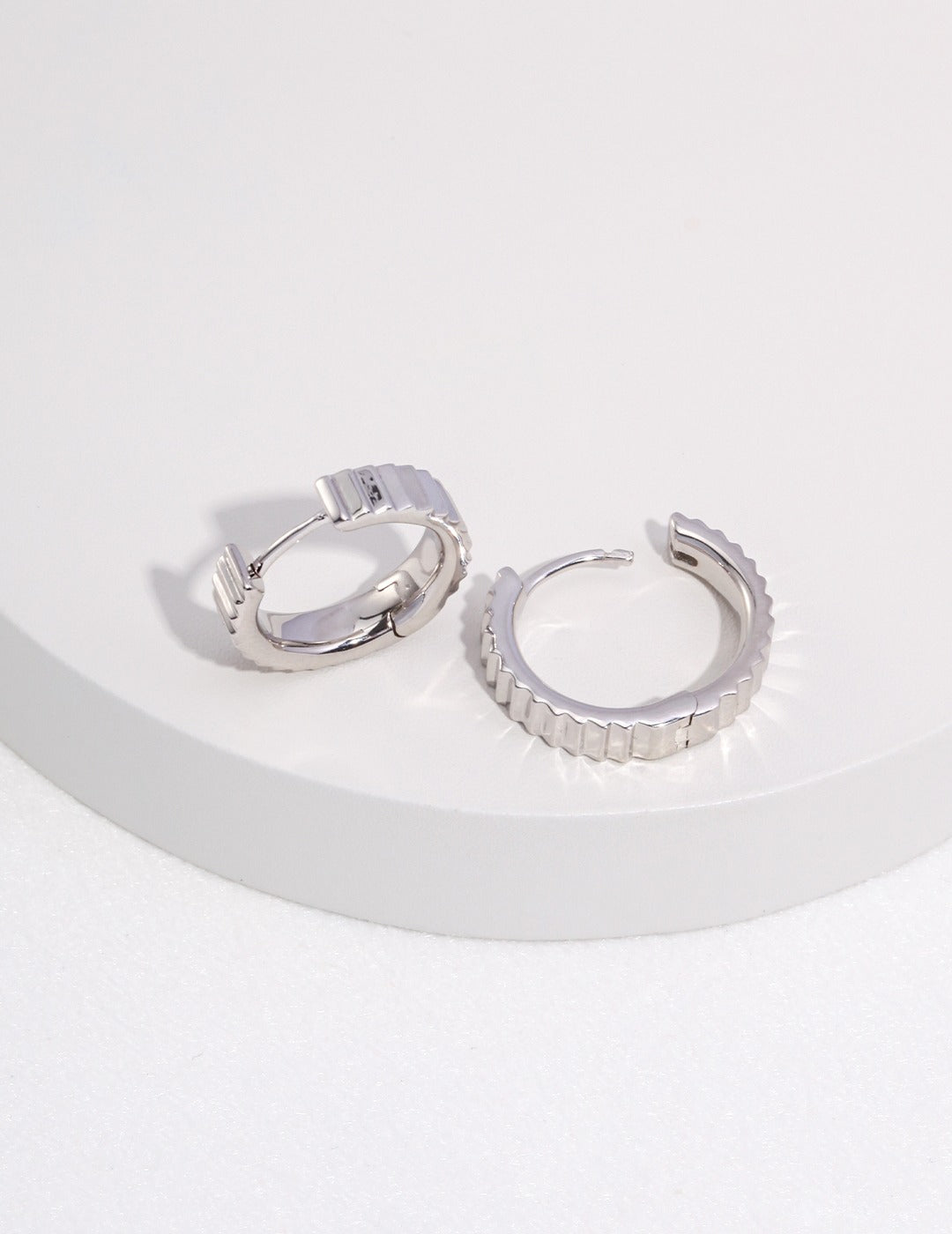 Shiny silver hoops on white background.