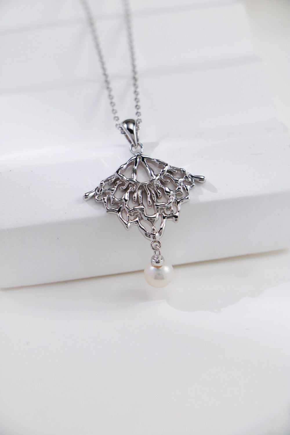 Chic silver necklace with a radiant pearl and delicate lacework, ideal for adding sophistication to any outfit.