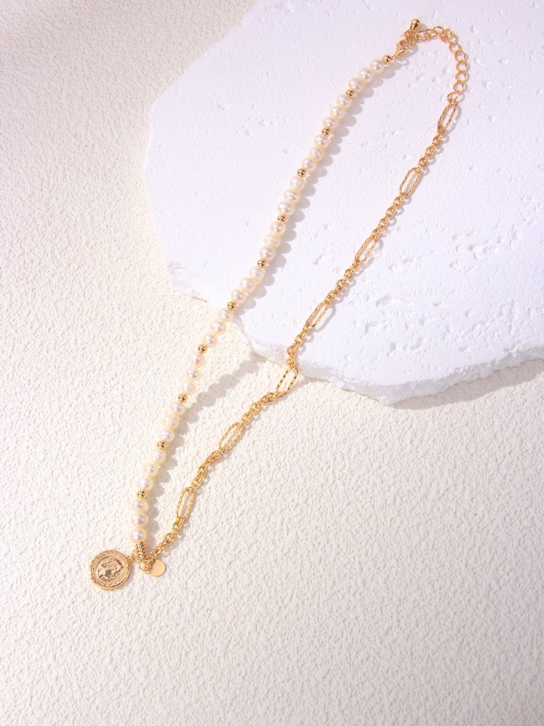 Elegant gold chain necklace adorned with pearl beads and a gold coin, perfect for adding a touch of luxury.

