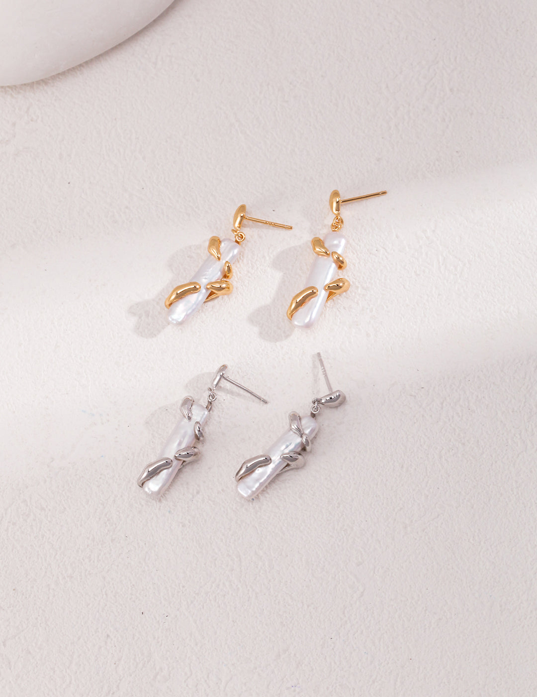 Elegant earrings featuring baroque pearls in silver and gold.