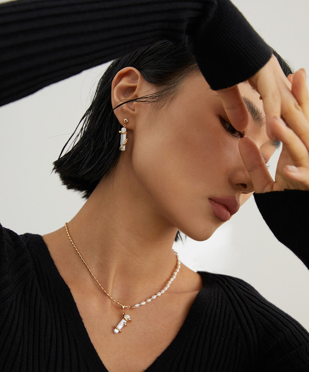 A model wearing a black sweater and a baroque pearls necklace.