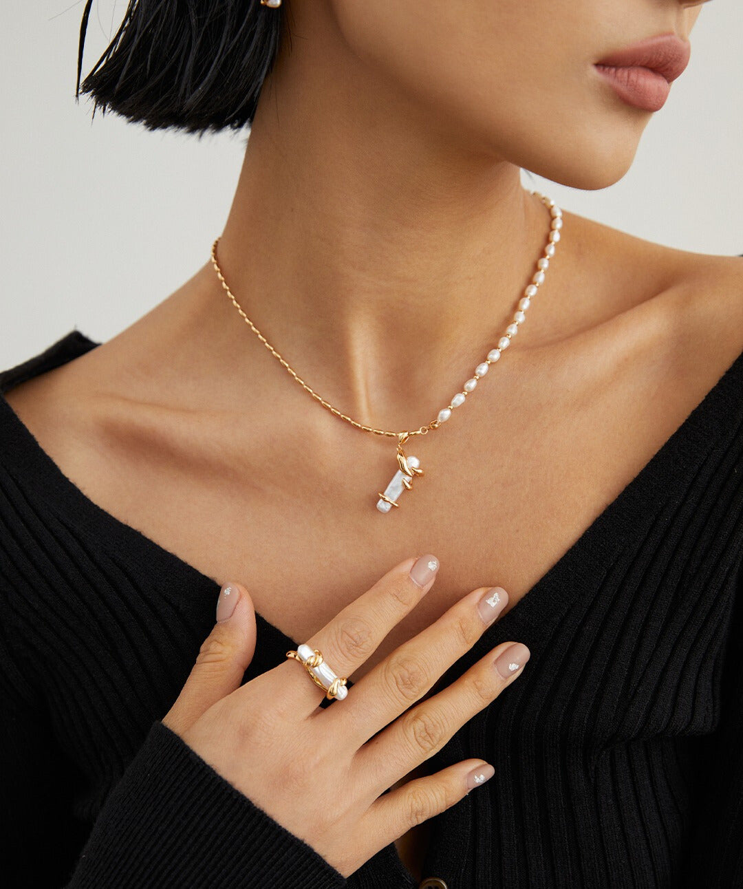 A woman wearing a pearl necklace and ring, with a gold plated freshwater pearl ring.