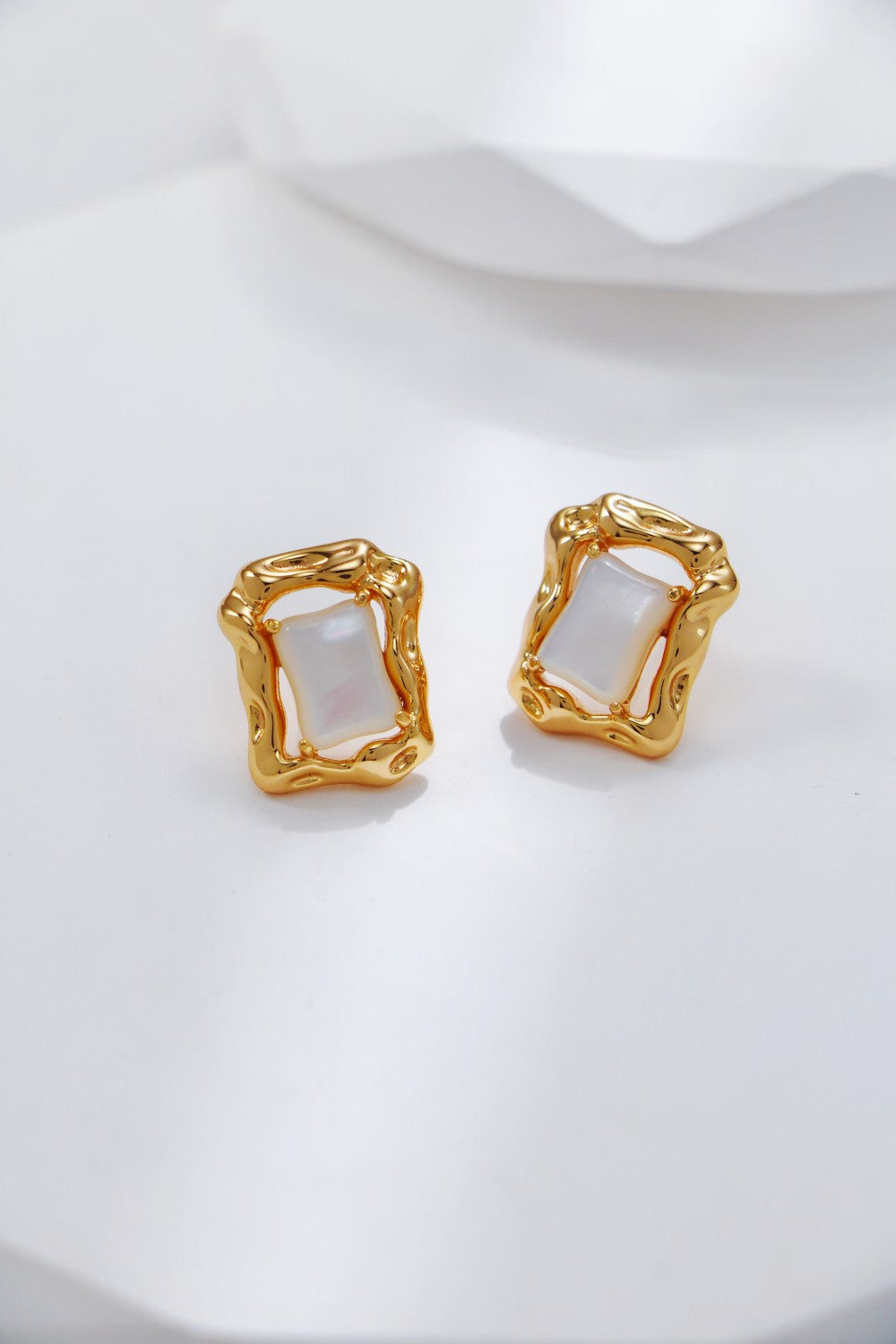 A pair of stylish gold tone square earrings, highlighting their modern geometric shape and shiny finish.