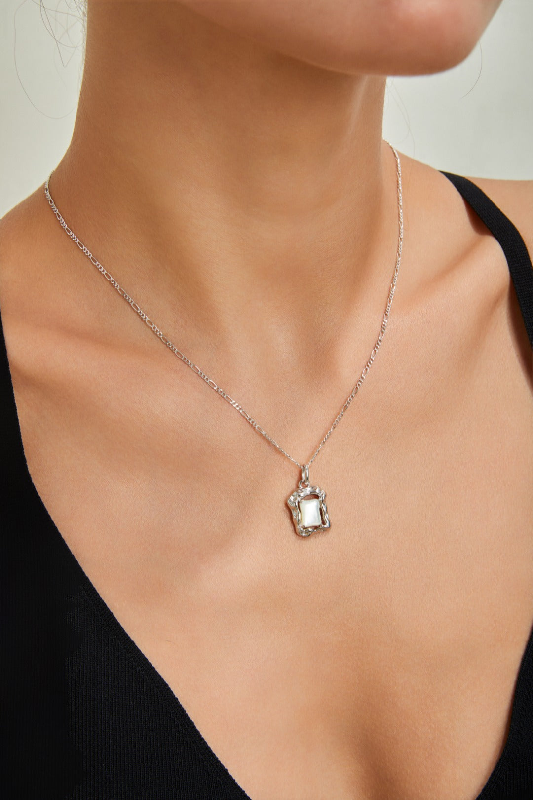 A woman adorned with a beautiful necklace, featuring a dazzling nacre pendant that enhances her graceful appearance.