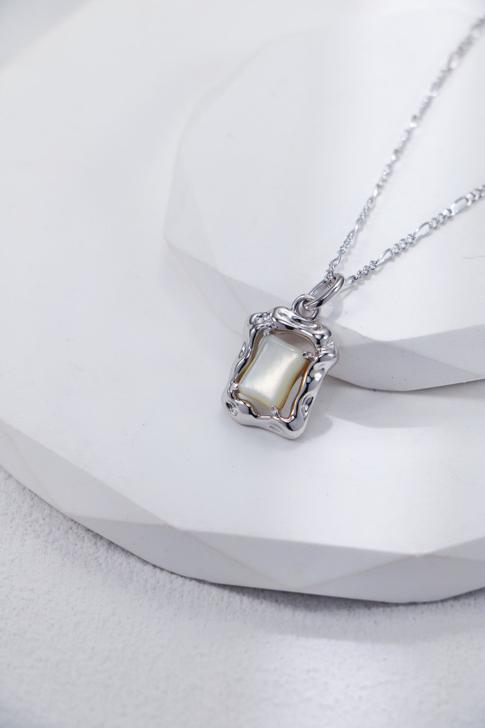 Elegant square silver necklace adorned with a lustrous mother of pearl stone, perfect for any occasion.
