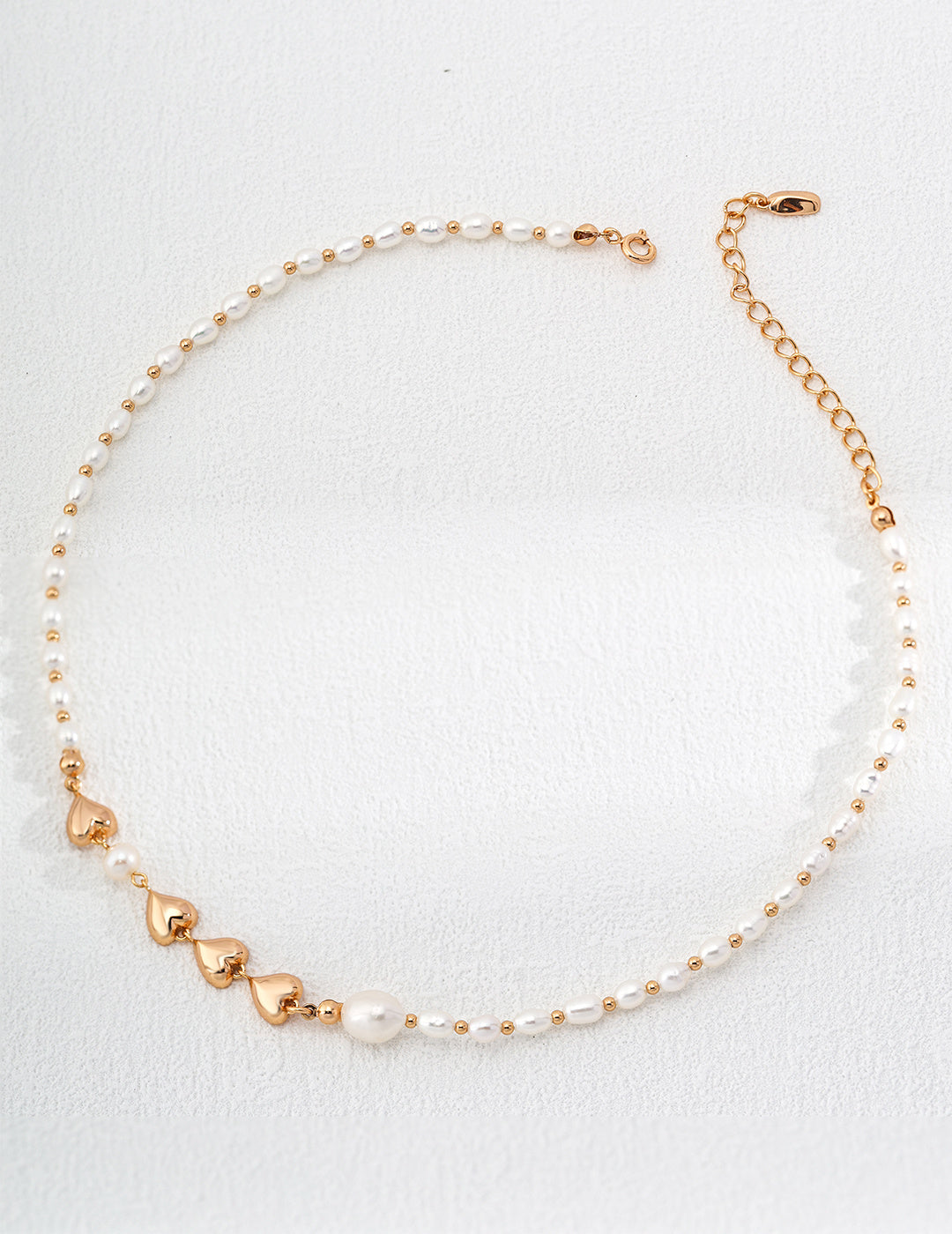 An exquisite gold and white pearl necklace laid out on a white surface, emphasizing its refined beauty and craftsmanship.