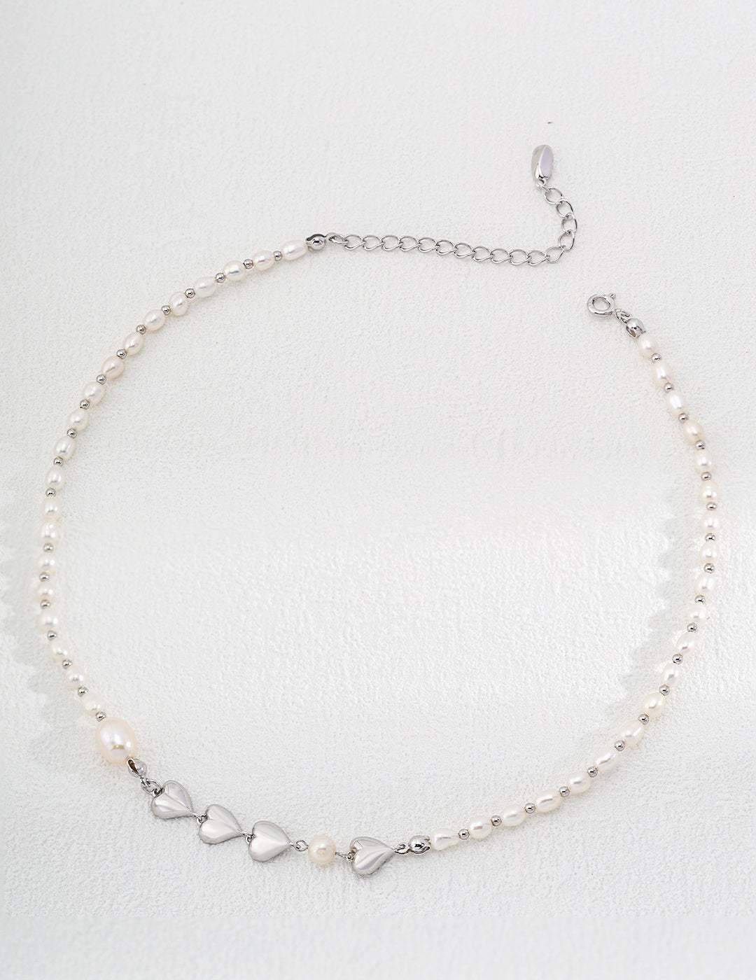 Charming pearl necklace with a heart-shaped pendant and a silver clasp, a lovely addition to any jewelry collection.