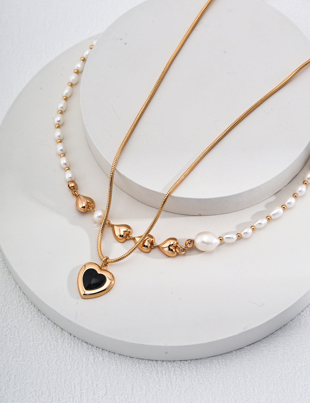 A beautiful gold necklace with a heart pendant, embellished with delicate pearls, ideal for adding charm to any outfit.