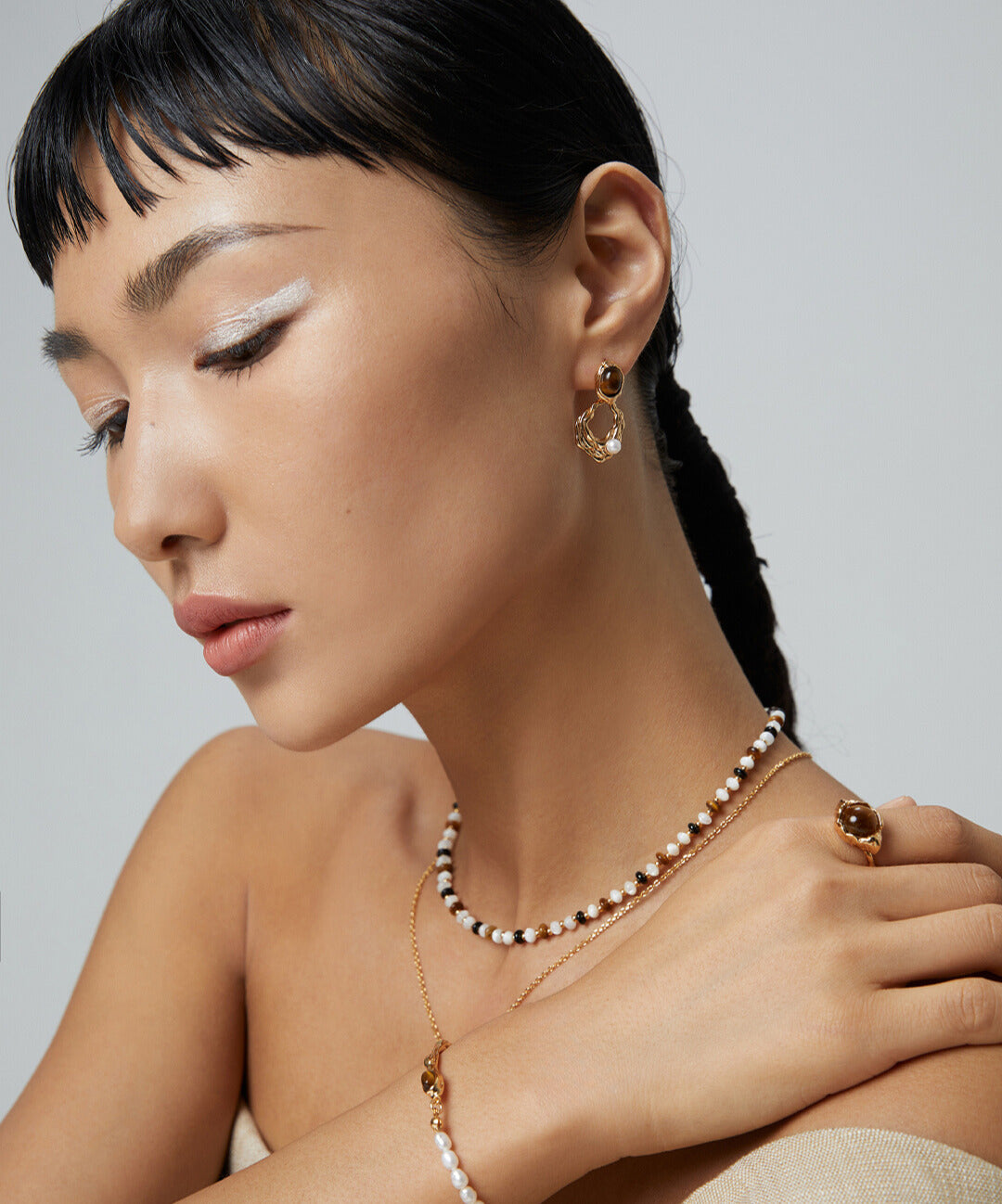 Model adorned with necklace and bracelet, showcasing gold plated tiger's eye freshwater pearls drop earrings.