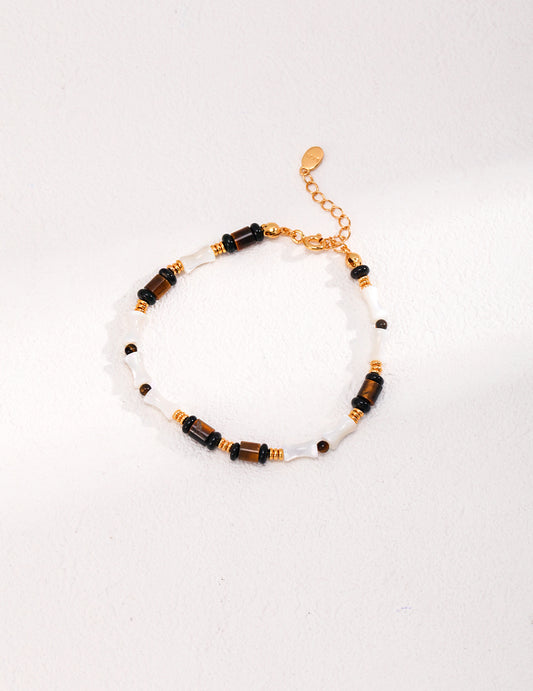 A stylish black and white bracelet adorned with gold and black beads, featuring gold plating, nacre, black agate, and tiger's eye.