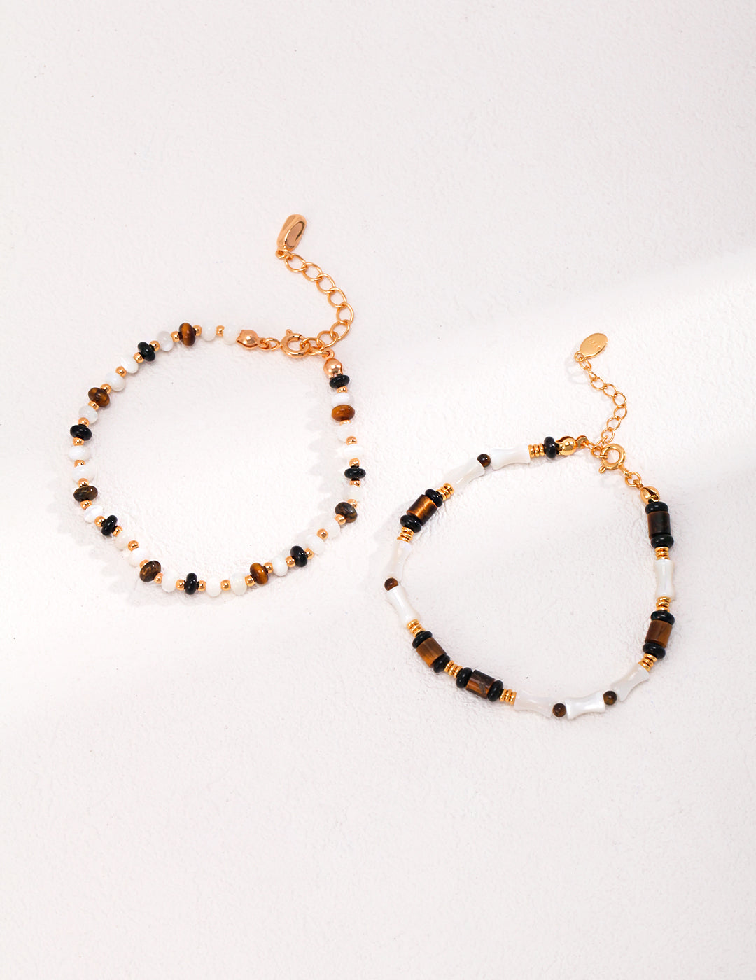 Two elegant bracelets with gold and black beads, featuring gold plated nacre, black agate, and tiger's eye stones.