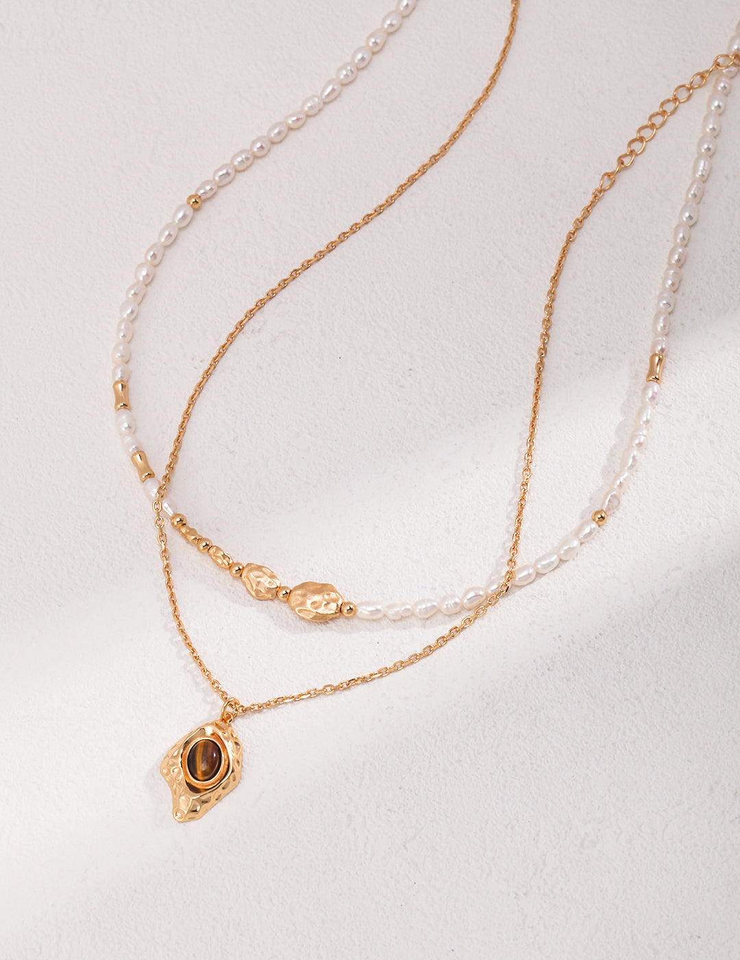 Gold necklaces with small pendant, featuring gold chain and petite freshwater pearl beads.