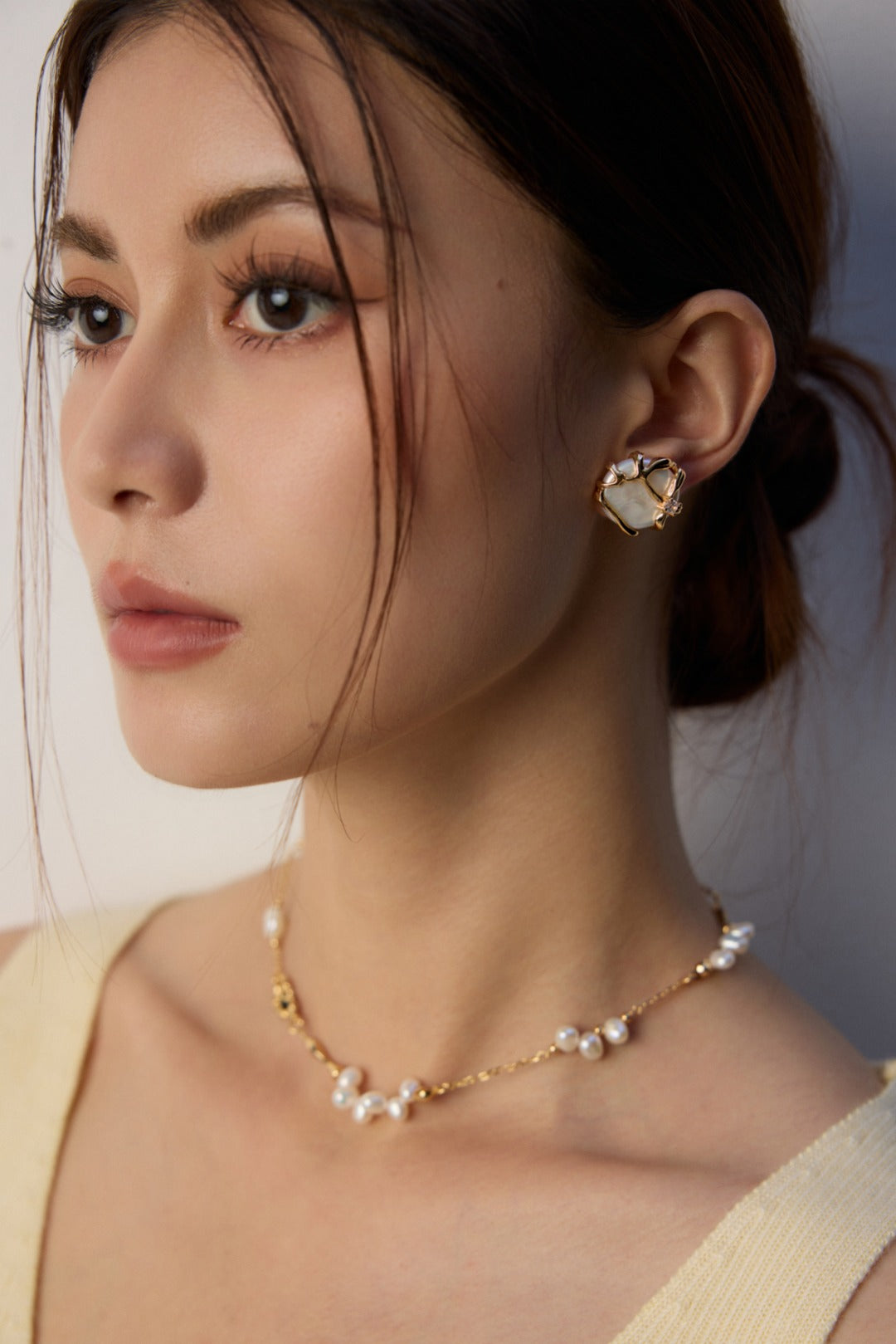 Profile view of a woman wearing the Alexi freshwater pearl studs and a matching pearl necklace from Mezuille.