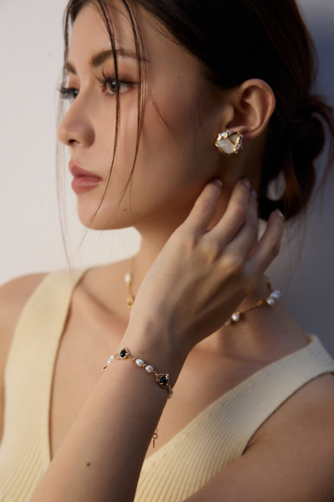 Lifestyle shot of our Alexi pearl studs and a gold pearl bracelet, highlighting the executive, minimalist aesthetic for daily wear.
