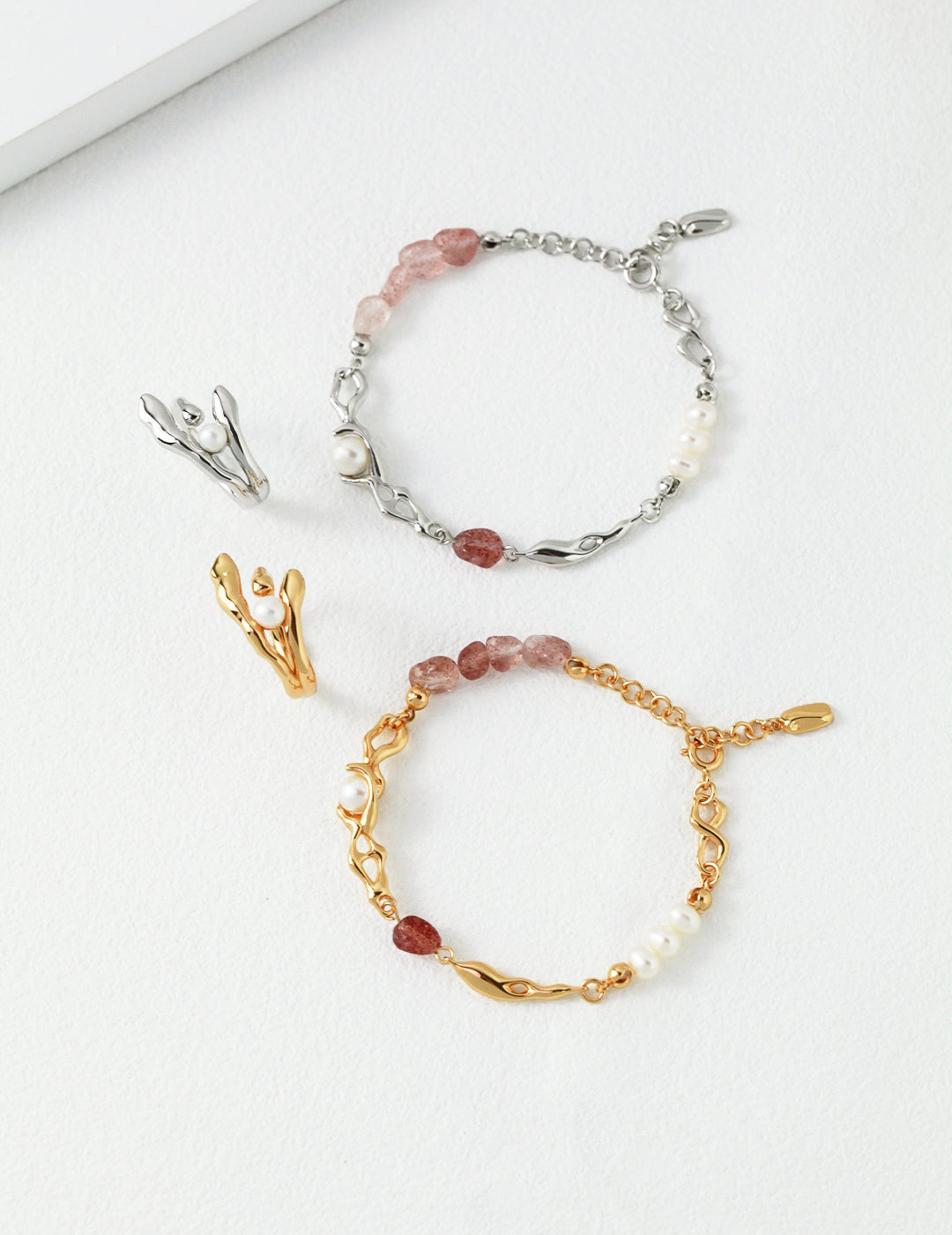 Two elegant bracelets with gold and silver charms, adorned with freshwater pearls and strawberry quartz, complemented by matching rings.