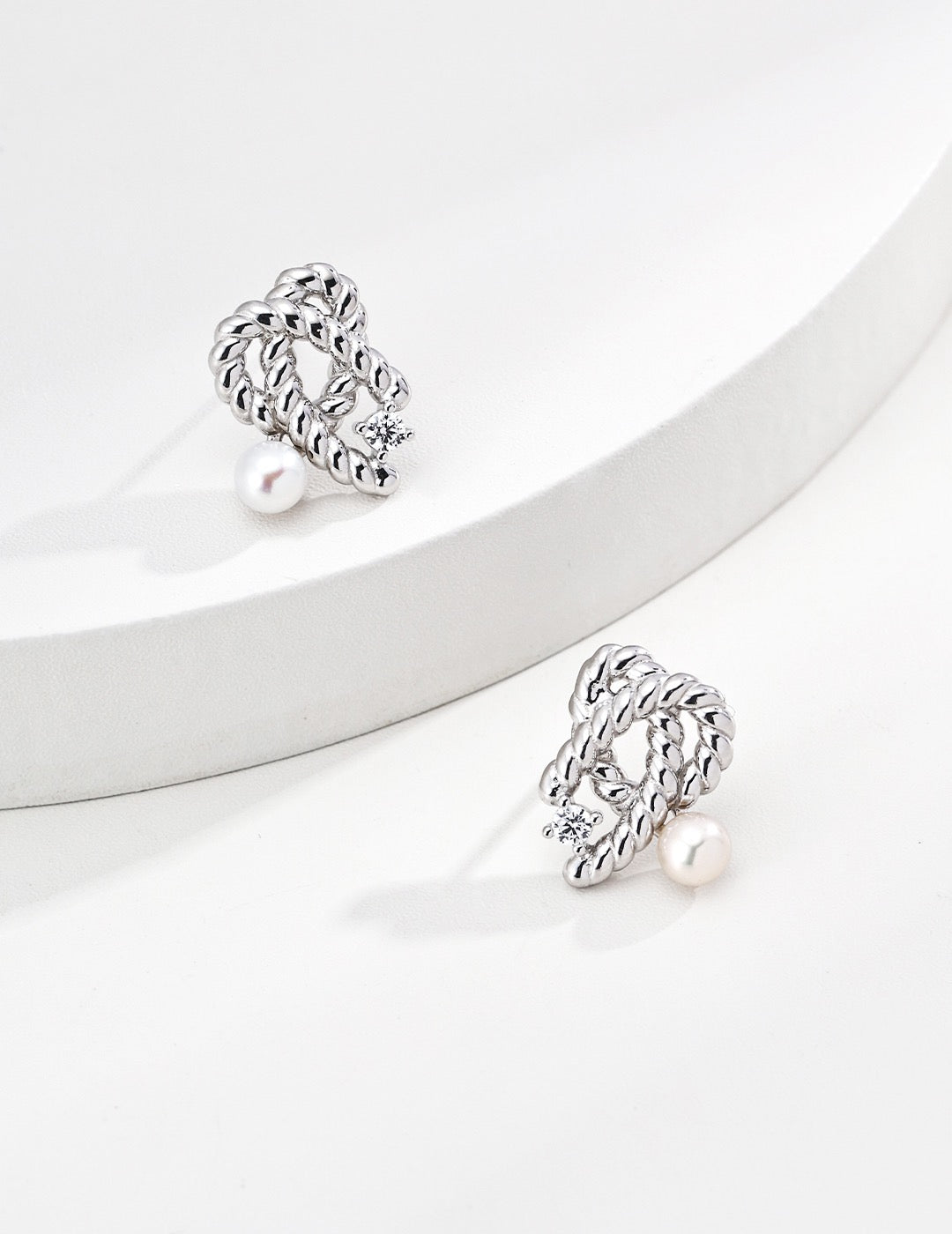 Detail-driven silver pearls studs by Mezuille on a white background.