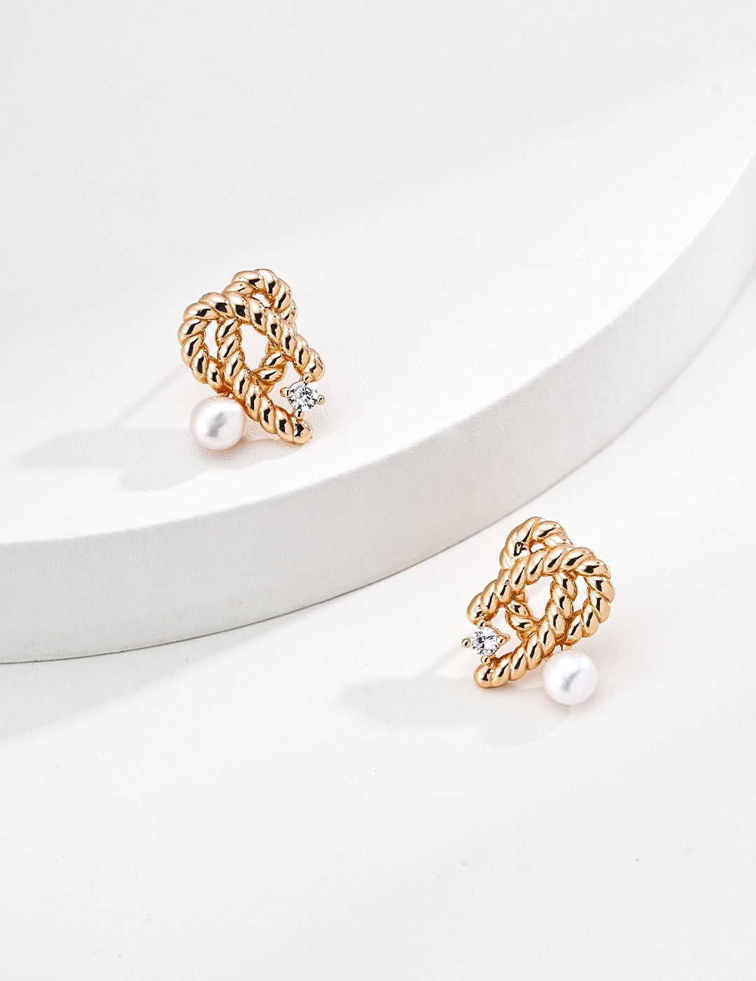 A pair of gold Mezuille studs with zirconia and pearls, sleek style.