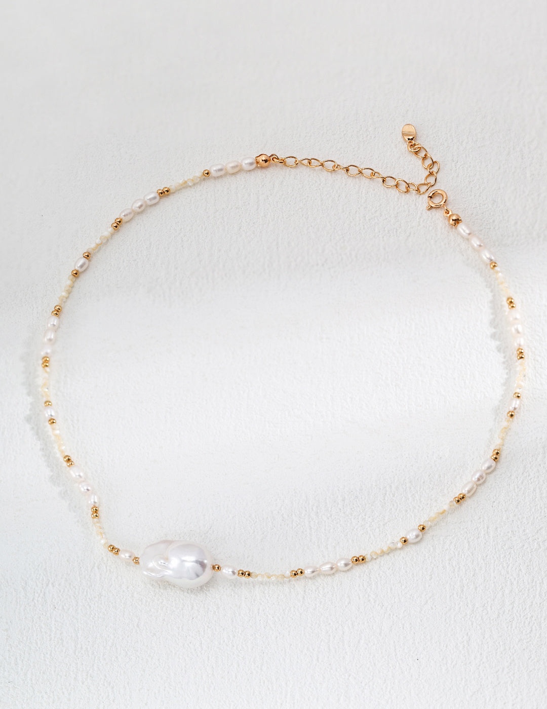 Beautiful gold and white pearl necklace resting on a delicate surface, emphasizing its elegance and sophisticated style.