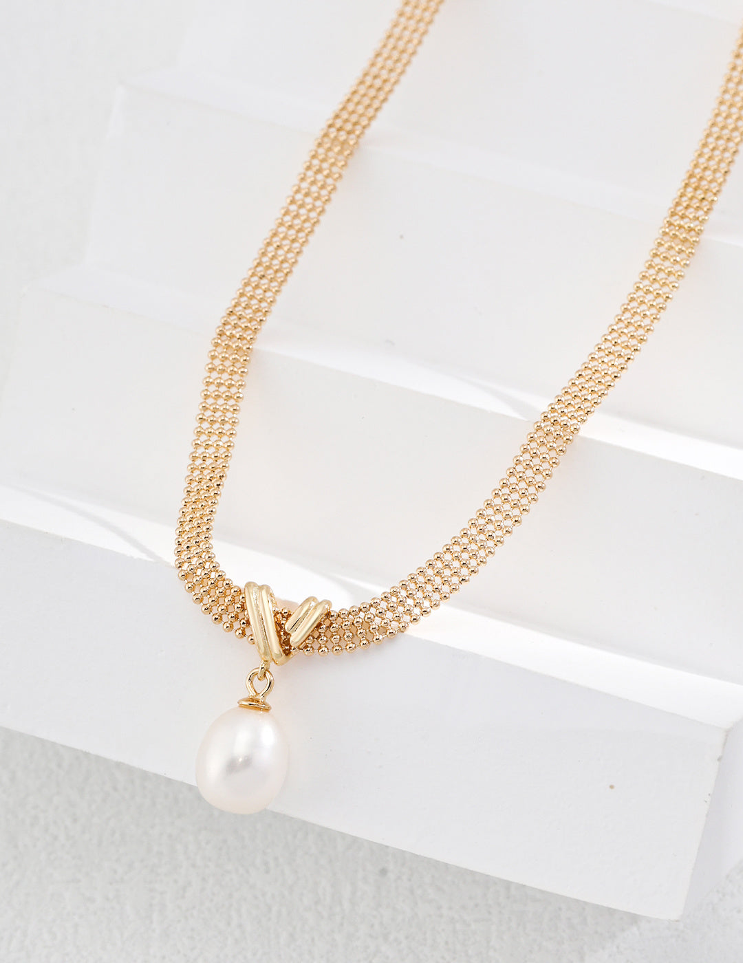 Elegant gold chain necklace adorned with a pearl and a gold pendant, perfect for adding a touch of luxury to any outfit.