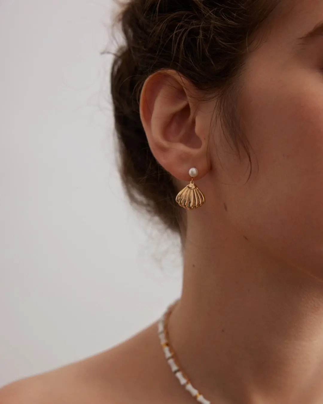 Elegant gold shell earrings featuring lustrous pearls, combining sophistication and natural beauty in a stunning design.