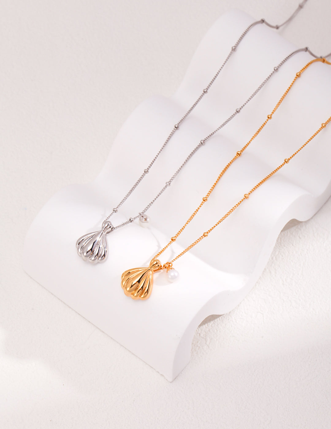 Two necklaces with a shell pendant, one in gold and the other in silver, beautifully crafted.