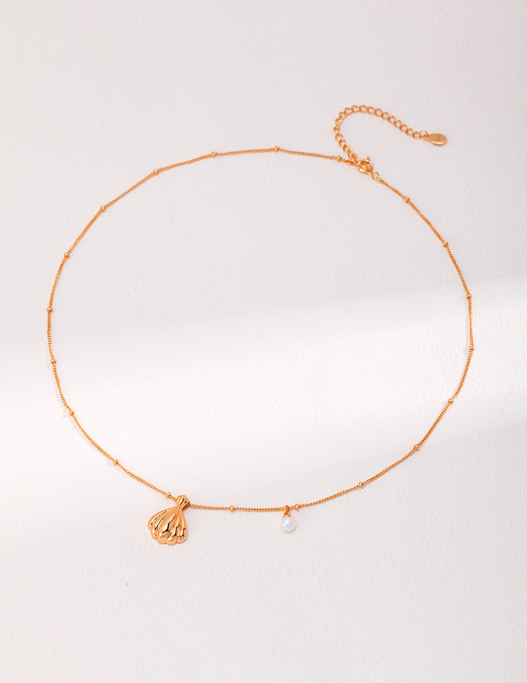 Gold plated necklace with charm and pearl pendant.